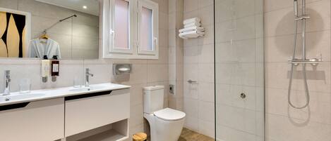 A modern bathroom with a glass-enclosed shower, a white sink with a mirror, and a toilet.