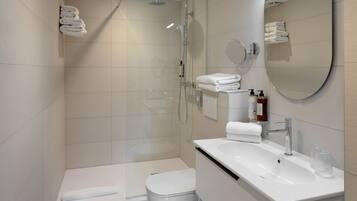 Une salle de bain moderne avec une douche à parois de verre, des toilettes blanches et un lavabo avec un miroir.