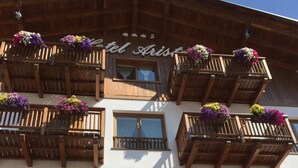 A hotel with balconies adorned with flowers and a sign reading "Hotel Ariston". - Hotel Ariston (Pinzolo)