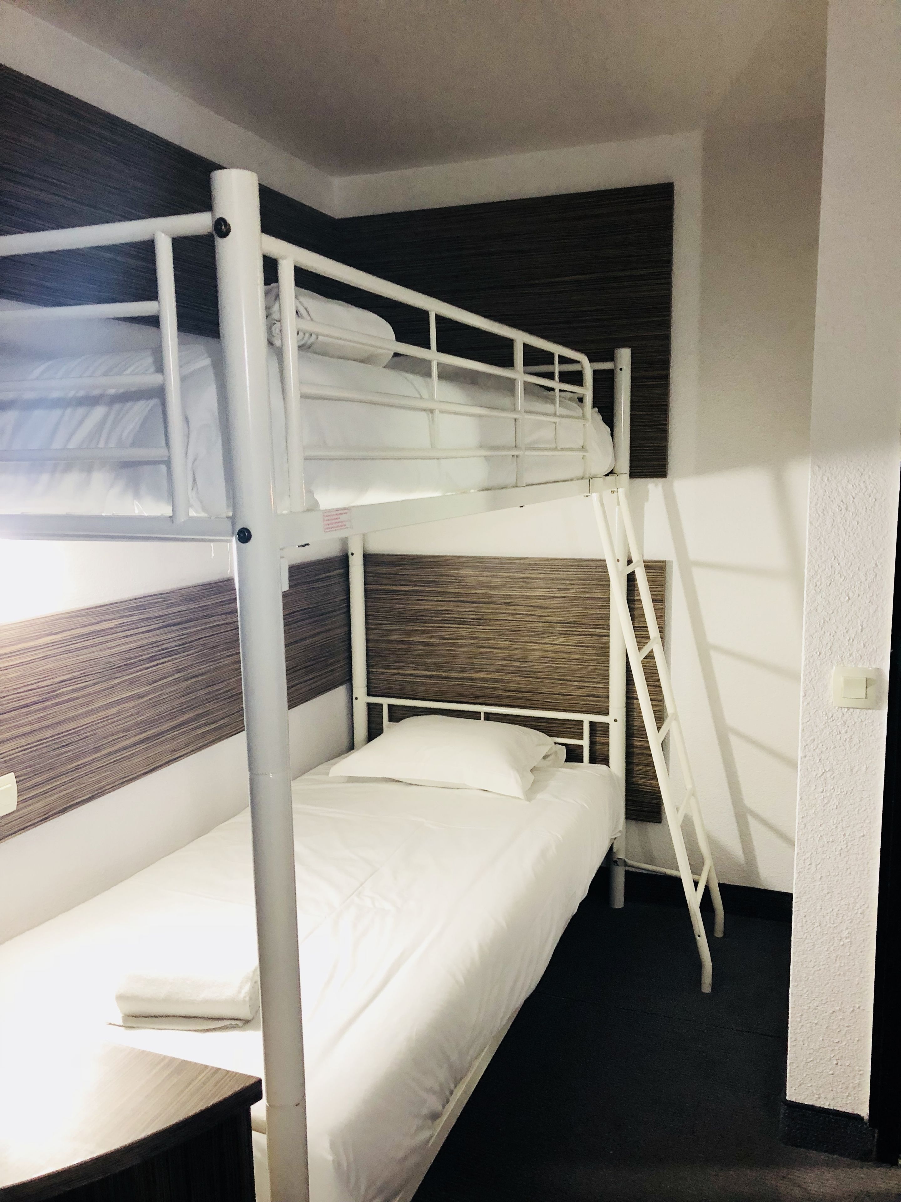 A bunk bed room with a wooden headboard, a white ladder, and a small table.