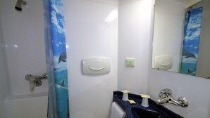 Une salle de bain avec un rideau de douche, un lavabo, un miroir et des toilettes.