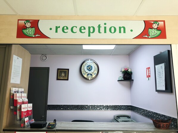 A reception area with a clock, framed picture, and a sign reading "reception." - Fasthôtel Noyelles Godault (Noyelles-Godault)
