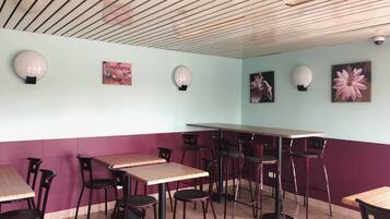 Un interior de restaurante con techo de madera, paredes azul claro y moradas, y varias mesas y sillas.