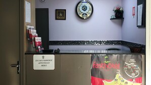 Un espace d’accueil comprenant une horloge, un plan de Paris et un panneau indiquant qu’il faut appuyer sur le bouton « ICI » en cas d’absence.