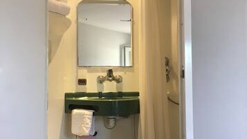 Ein Badezimmer mit einer weißen Toilette, einem grünen Waschbecken, einem Spiegel und einer Duschvorhang.