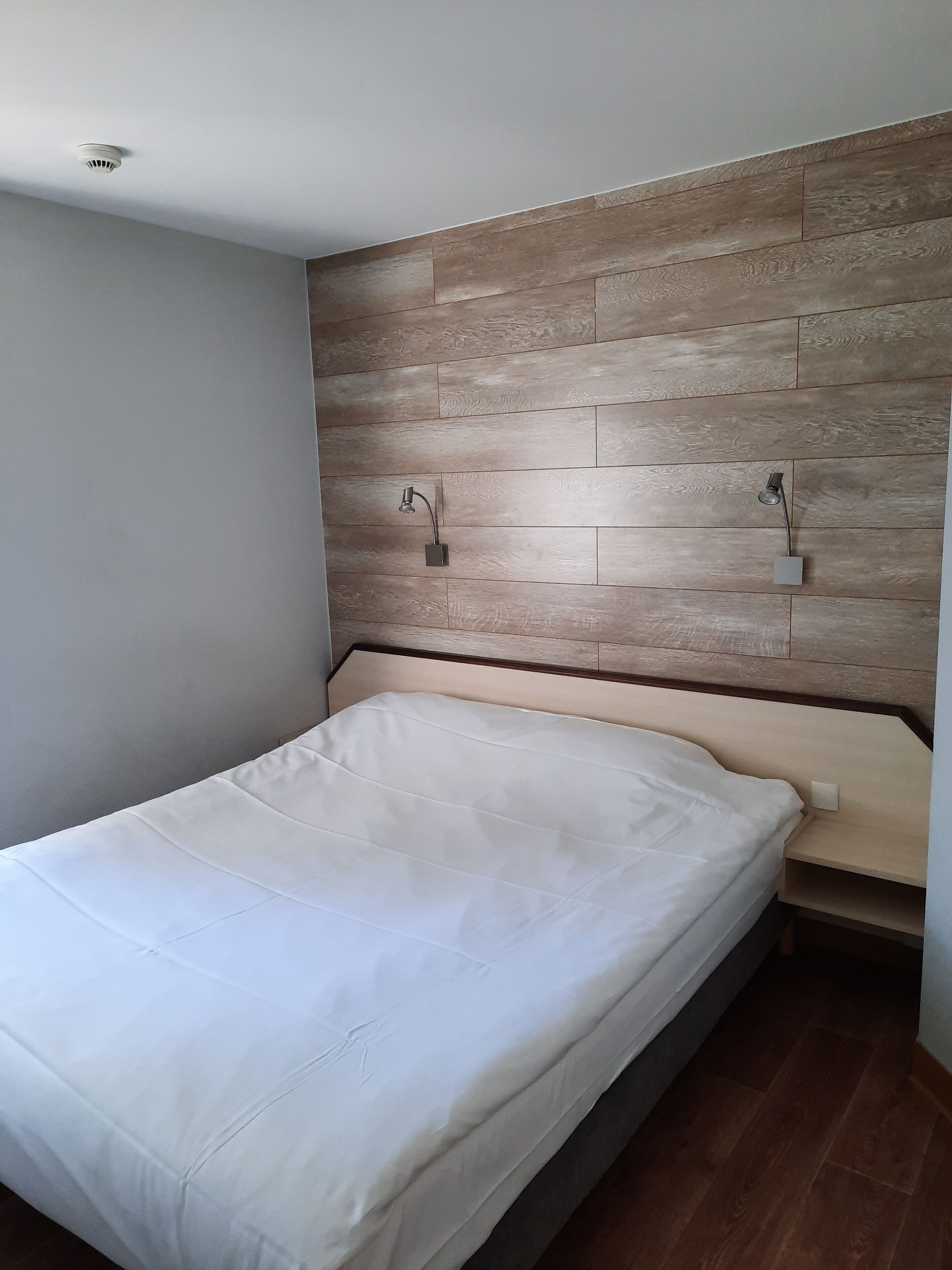 Une chambre à coucher avec une tête de lit en bois, un lit simple et une table de chevet.