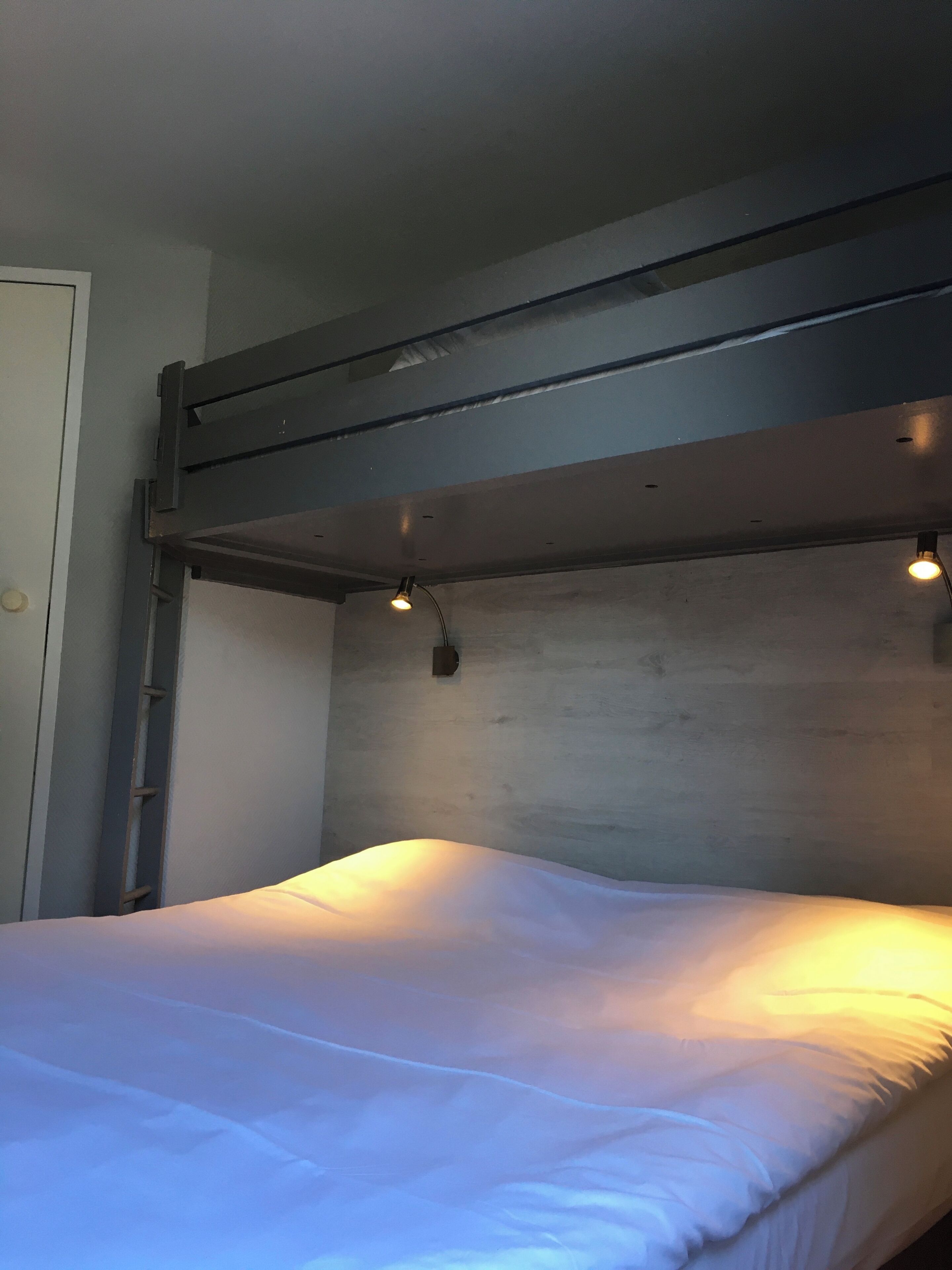 A bunk bed with a metal headboard and a single light fixture above it.
