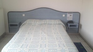 Un dormitorio con cama, dos mesitas de noche e iluminación en la pared.