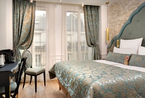Habitación de hotel con una cama grande, un escritorio con silla y vistas al exterior a través de una ventana con cortinas.