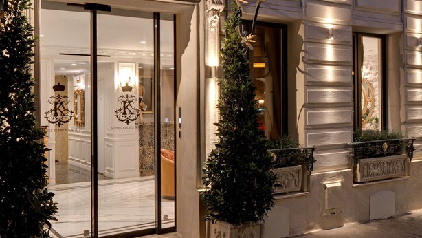 A hotel entrance with ornate ironwork, a glass canopy, and a Christmas tree. - Hôtel Kleber Paris & Spa (Paris)