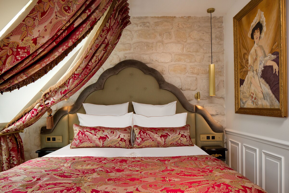 Una cama con una colcha estampada, un cabecero con un diseño decorativo y un cuadro en la pared.