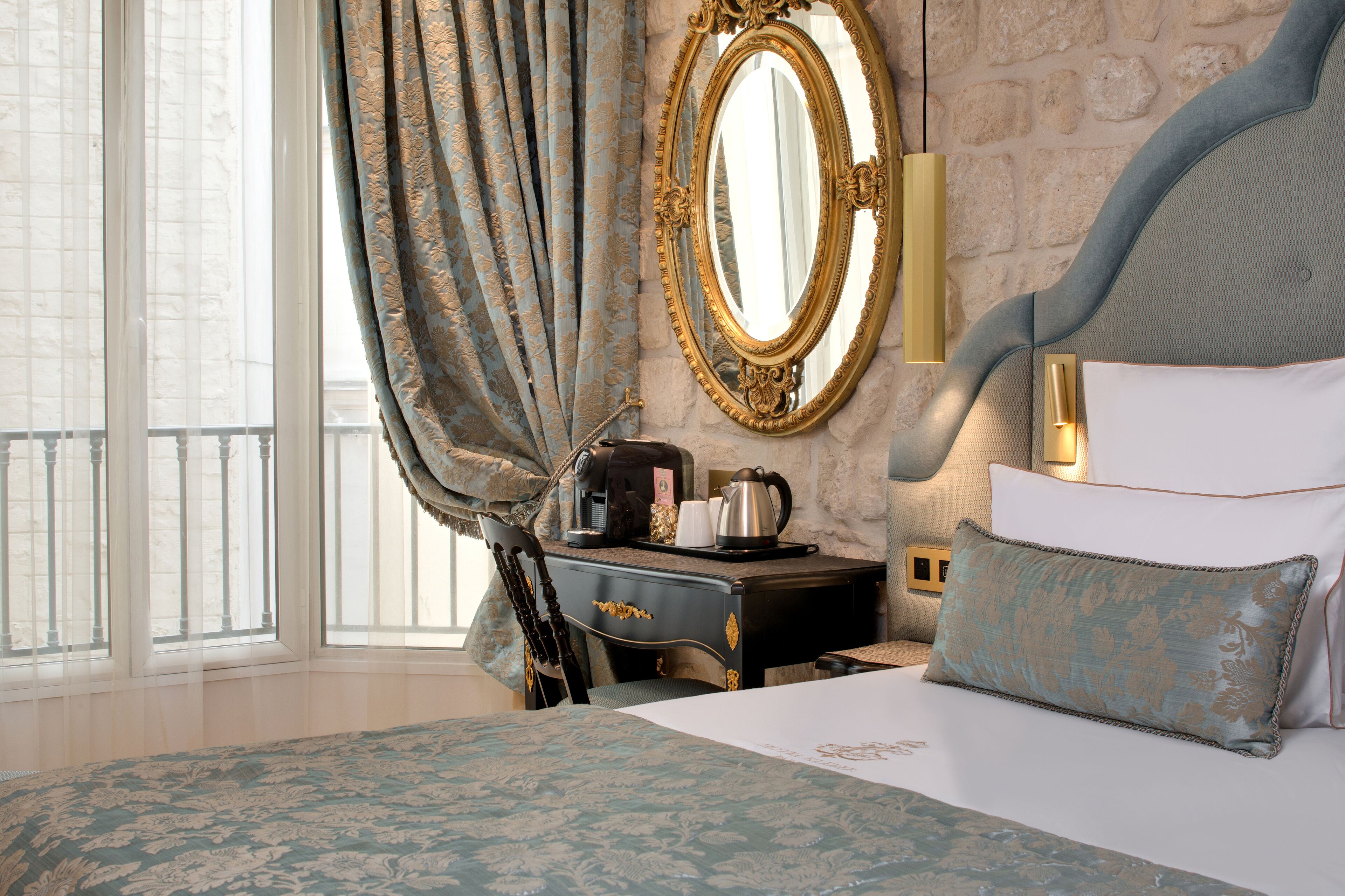 A hotel room with a large bed, a dresser, a mirror, and a view of the outside.