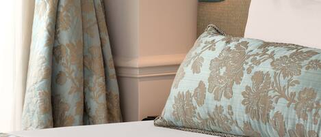 A bedroom with a bed, curtains, a headboard, and a pendant light.
