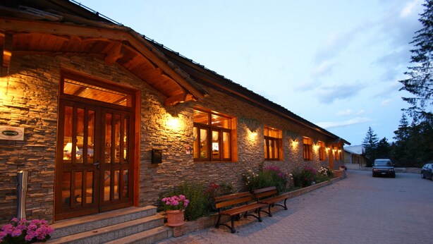 A stone building with a wooden door and windows, a bench, and potted plants. - Europa (Bardonecchia)