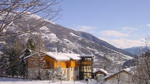 A snow-covered mountain landscape with a modern lodge featuring a large glass facade and wooden structures. - Europa (Bardonecchia)
