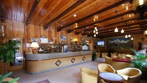 A wooden interior with a bar area, seating, and a television screen. - Europa (Bardonecchia)