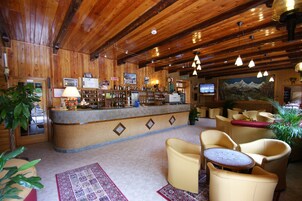 Un interior de madera con una zona de bar, asientos y una pantalla de televisión.