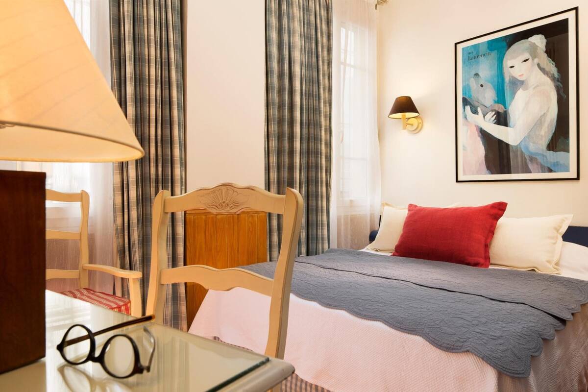 Ein Hotelzimmer mit einem Bett, einem Sessel, einem Tisch mit Gläsern und einem Bild an der Wand.