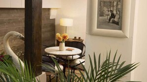 A cozy room with a round table, chairs, a vase with flowers, a lamp, and a framed picture on the wall. - Hotel du Cygne Paris (Paris)