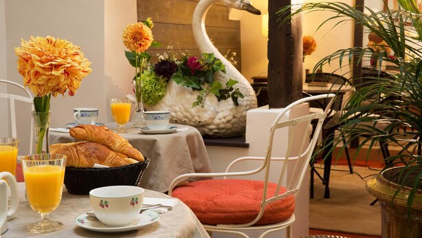 A breakfast setup with croissants, orange juice, and a swan-shaped vase with flowers. - Hotel du Cygne Paris (Paris)