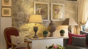 A cozy room with a stone wall, a wooden chair, a sofa, and two lamps. - Hotel du Cygne Paris (Paris)