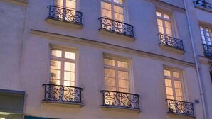 A multi-story hotel with balconies, large windows, and a blue awning. - Hôtel des Deux-Iles - Notre-Dame (Paris)