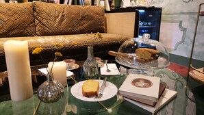 A dining table with a cake, a candle, a vase with flowers, and books. - Hôtel des Deux-Iles - Notre-Dame (Paris)