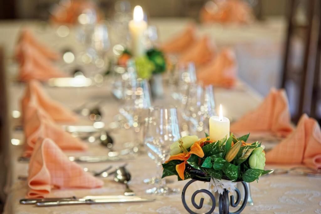 A table set with glassware, a candle, and a floral centerpiece.