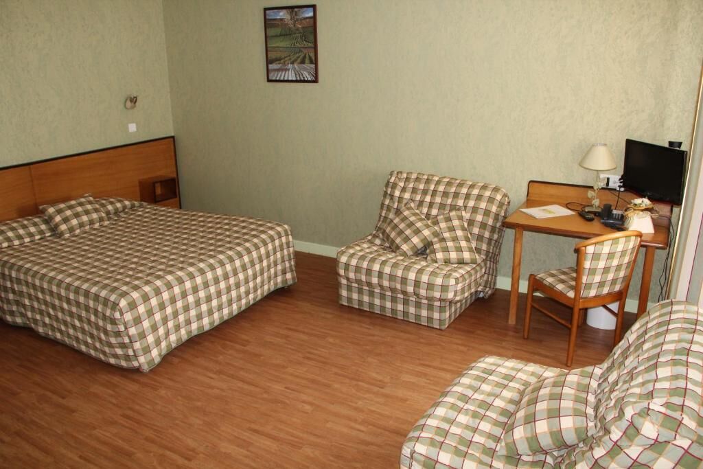 A room with two single beds, a chair, a small table, and a television.