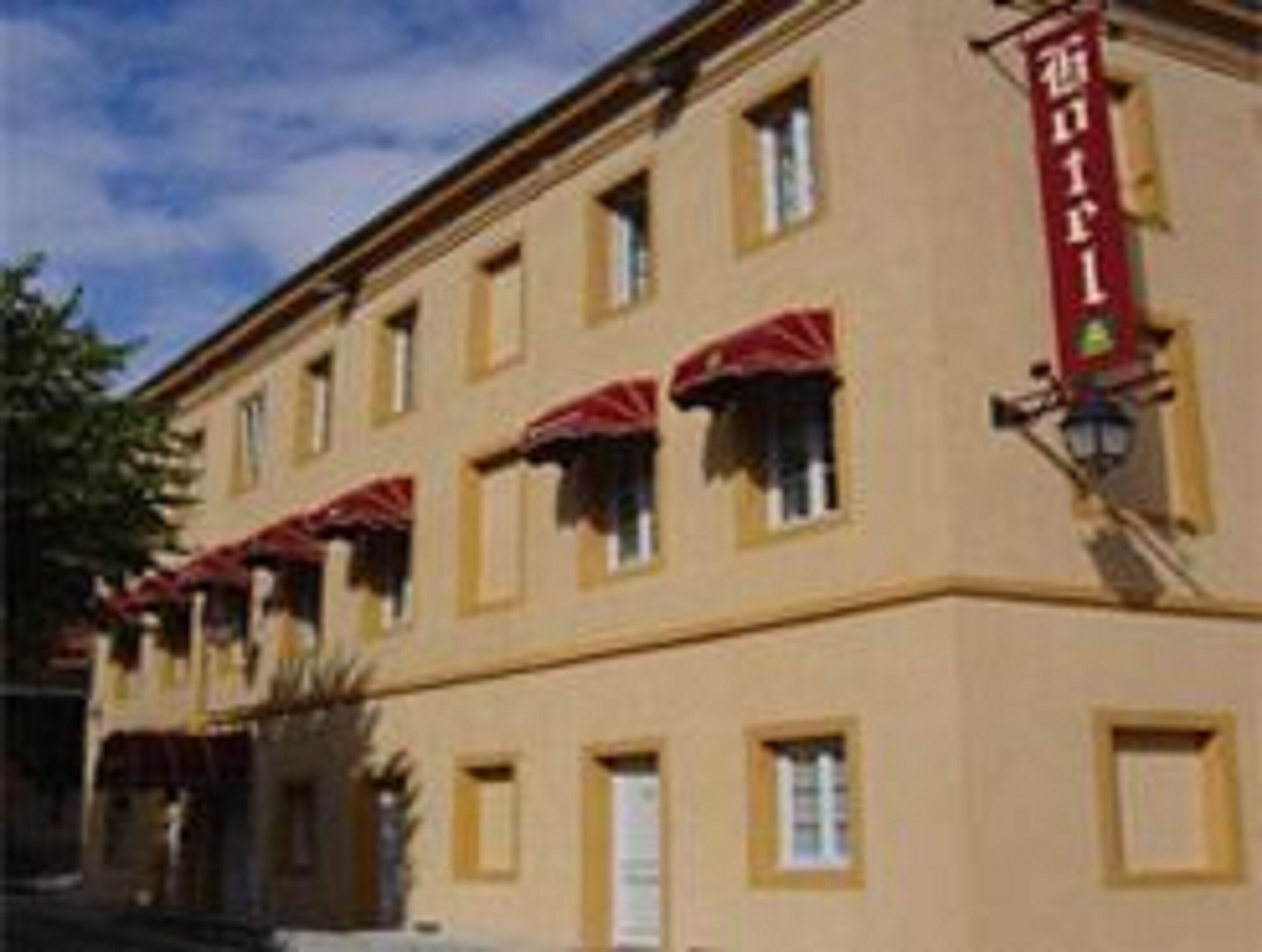 A building with a yellow facade, multiple windows, and red awnings.