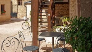 Un patio al aire libre con un edificio de piedra, una escalera y macetas colgantes.