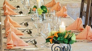 Una mesa dispuesta para una cena formal, con copas de cristal, servilletas dobladas y un centro de mesa con flores y velas.