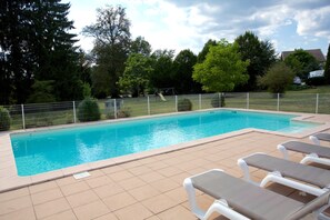 En säsongsöppen utomhuspool och solstolar