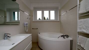 Un baño moderno con bañera, lavabo y ventana.