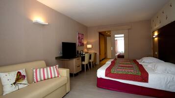 Une chambre d’hôtel comprenant un lit, un bureau, une télévision, un canapé et un fauteuil.