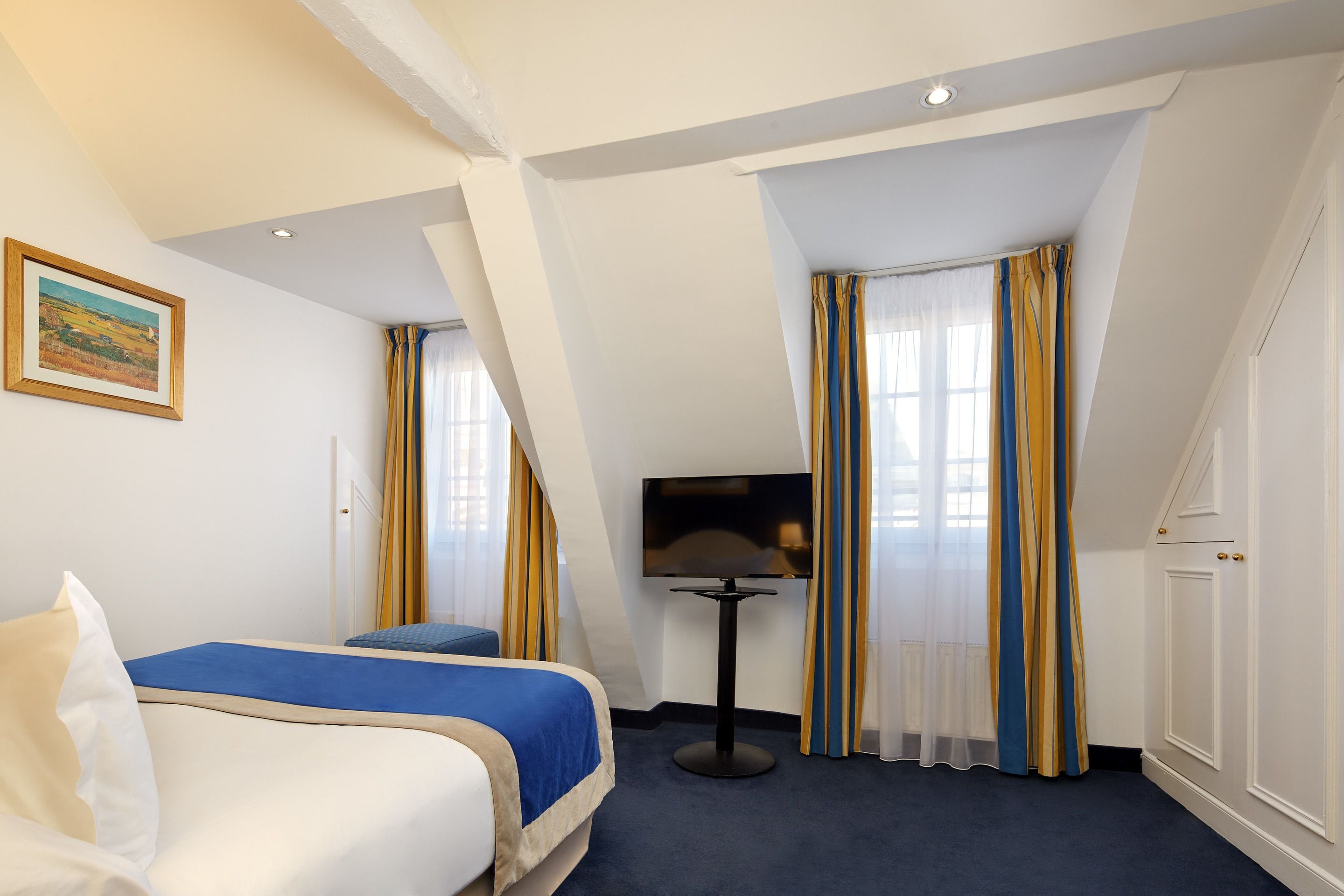 Une chambre d’hôtel avec un lit, une télévision et une fenêtre avec des rideaux.
