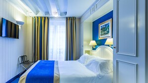 A hotel room with a bed, a TV mounted on the wall, a lamp, and a painting on the wall. - Austin's Arts et Métiers Hôtel (Paris)