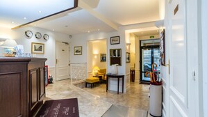 A hotel lobby with a reception desk, a seating area, and a door leading to the parking garage. - Austin's Arts et Métiers Hôtel (Paris)