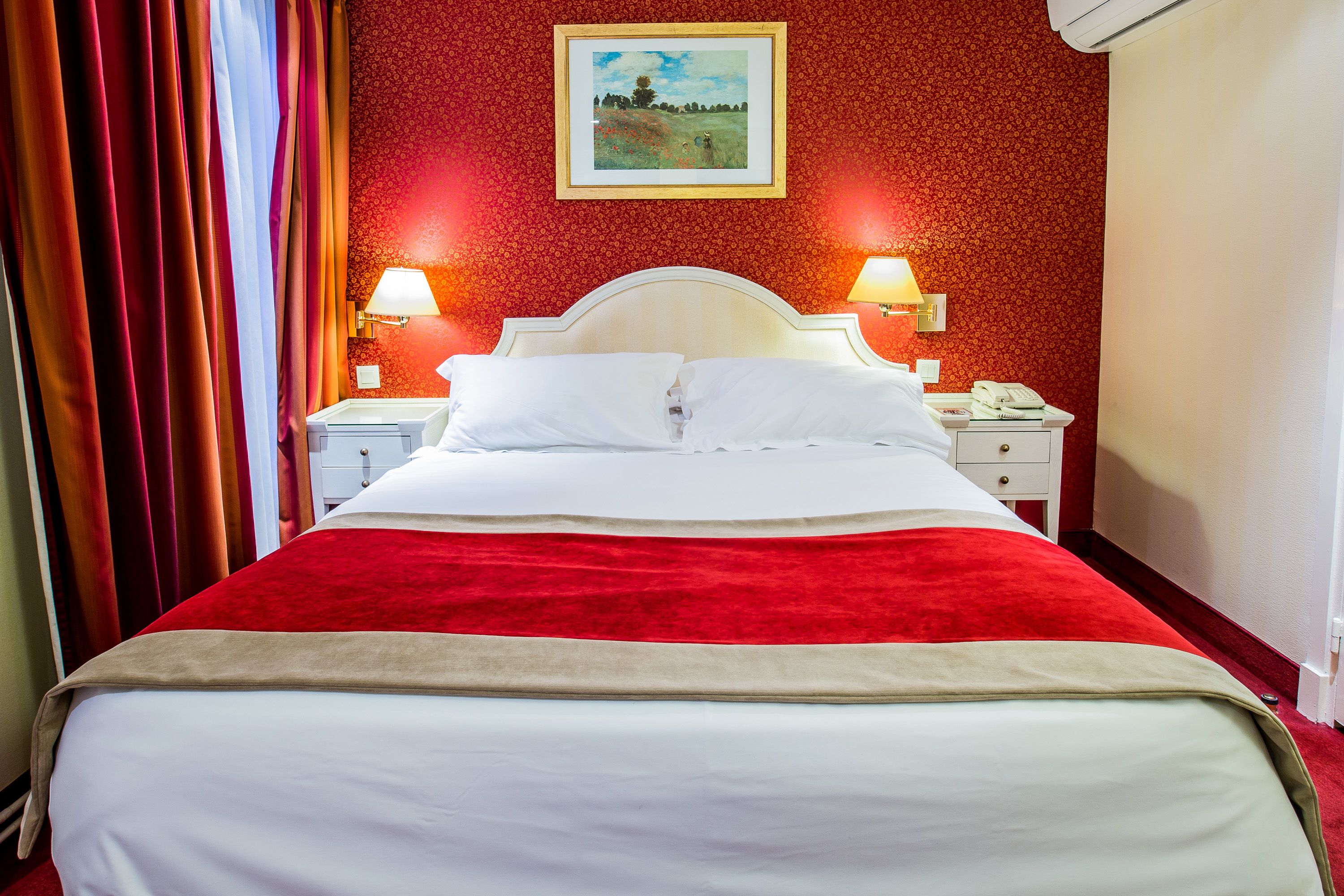 Una habitación de hotel con una cama grande, dos mesitas de noche con lámparas y un cuadro en la pared.