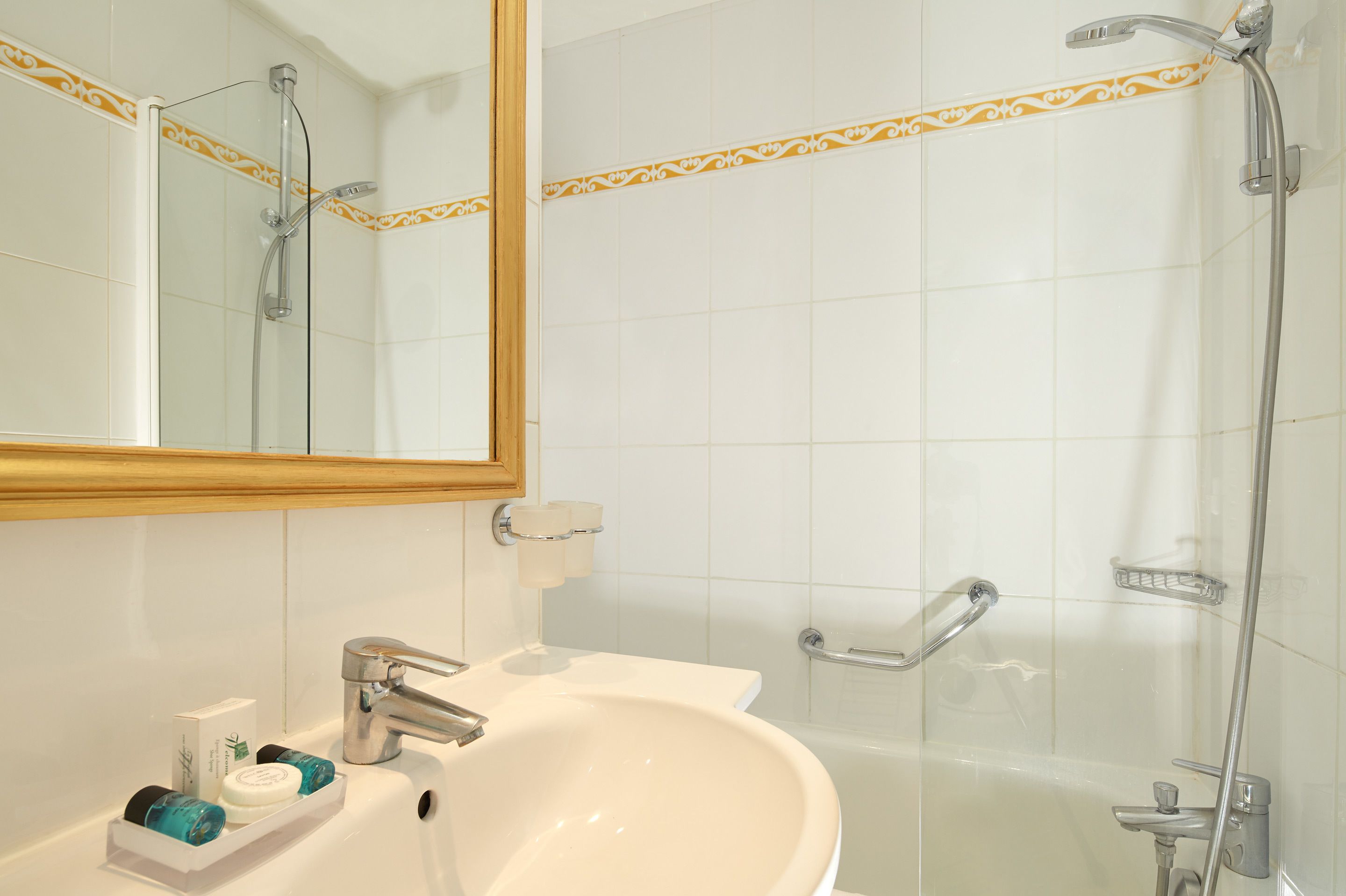 Une salle de bain avec un lavabo blanc, un miroir et une douche.