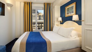 Habitación de hotel con cama, cortinas, un cuadro y vistas al exterior.