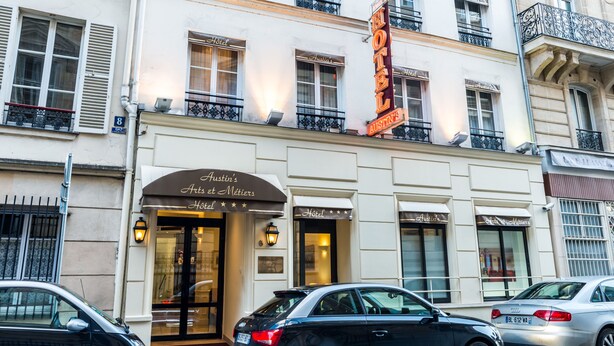 A hotel with a classic facade, multiple balconies, and a prominent neon sign. - Austin's Arts et Métiers Hôtel (Paris)
