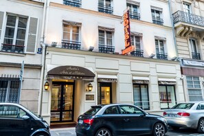 A hotel with a classic facade, multiple balconies, and a prominent neon sign.