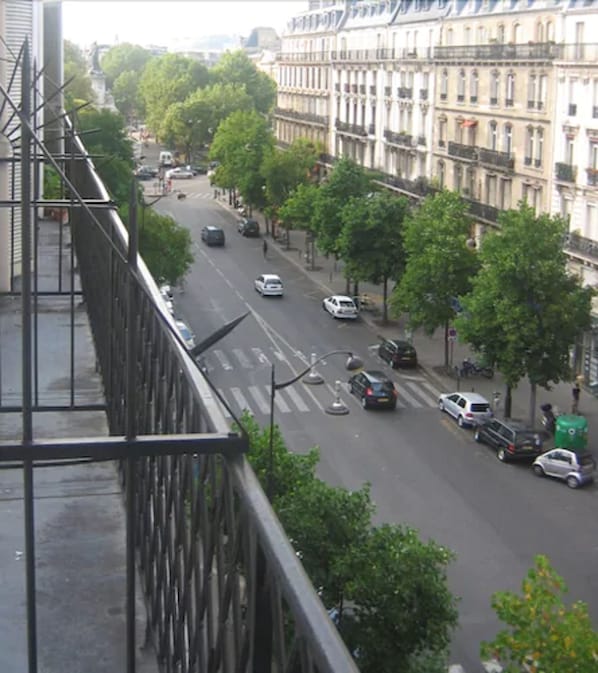 Vista de la calle con edificios, coches y árboles.