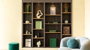 Un interior moderno con el letrero de Midnight Hotel, que presenta una escultura central, estanterías con adornos y un pouf verde.