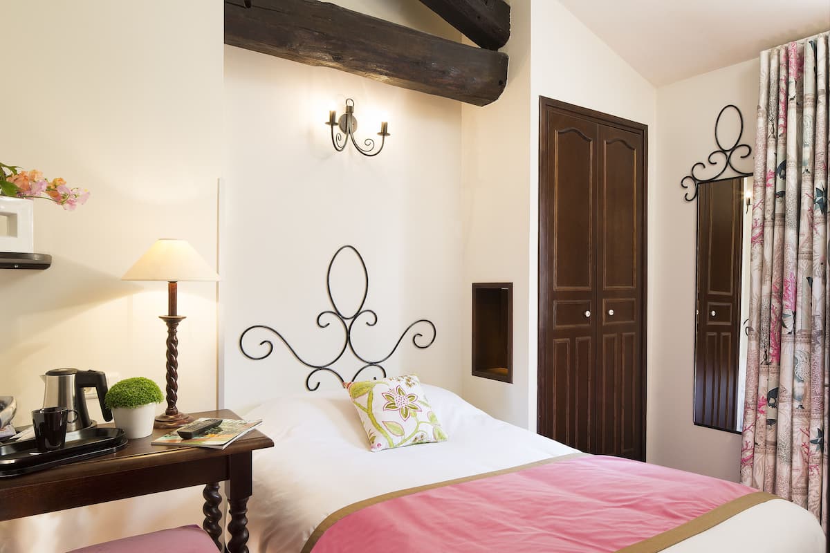 A neatly arranged bedroom with a bed, bedside table, lamp, and a small potted plant.