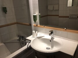 Ett badrum med ett vitt handfat, en spegel och en dusch.