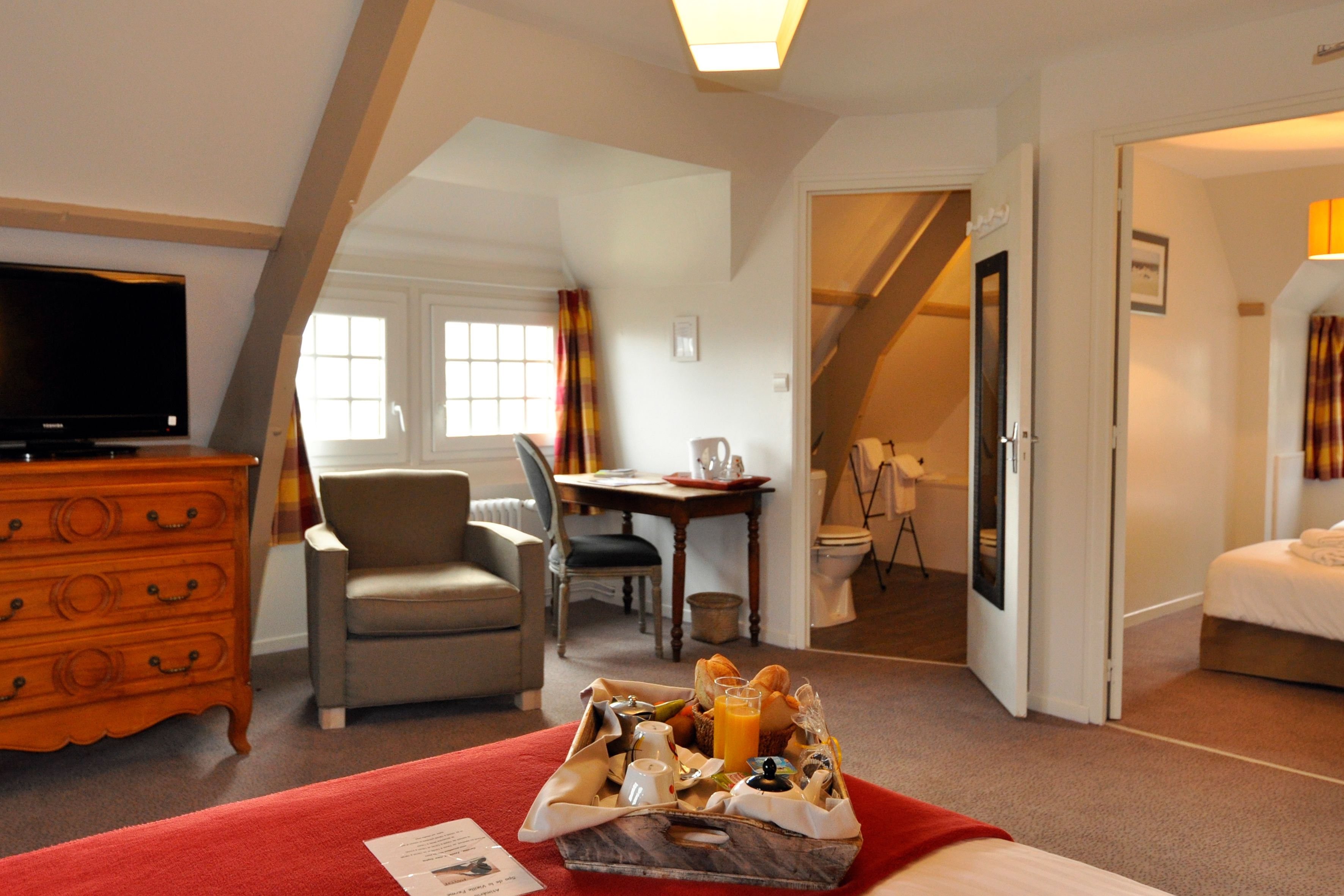 A hotel room with a bed, a TV, a dining area, and a bathroom.