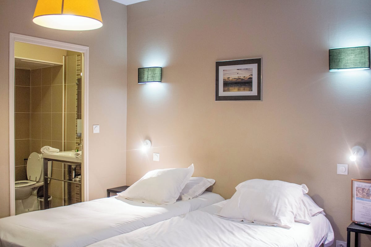 Une chambre d’hôtel avec un lit, une salle de bain et une petite table avec une chaise.