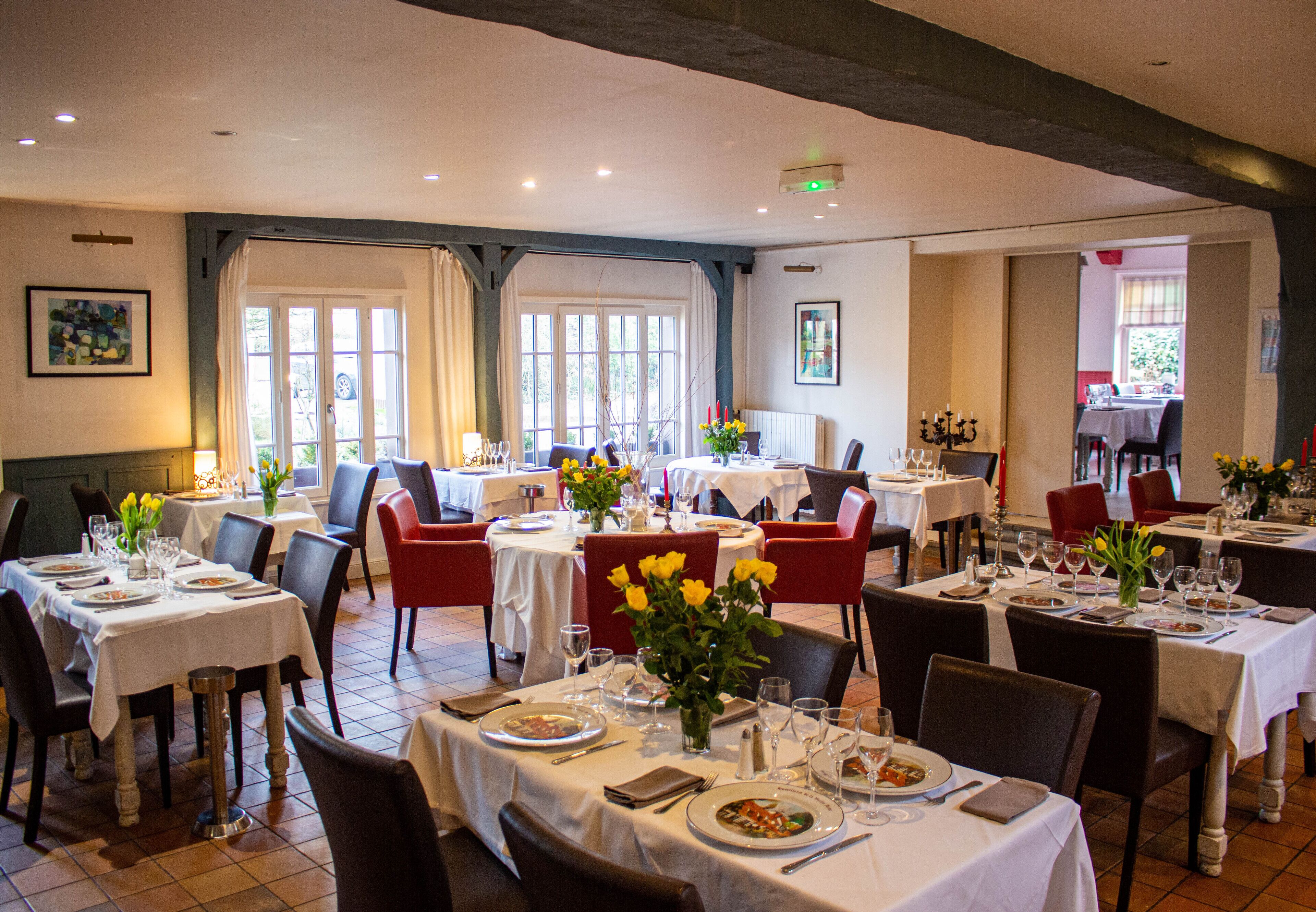 A dining area with multiple tables set for meals, chairs, and a window providing natural light.